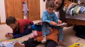 Girl reading to children in bedroom