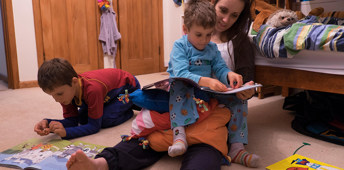 Girl reading to children in bedroom