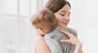 Young single mother lulling cradling her little small son daughter toddler infant newborn baby