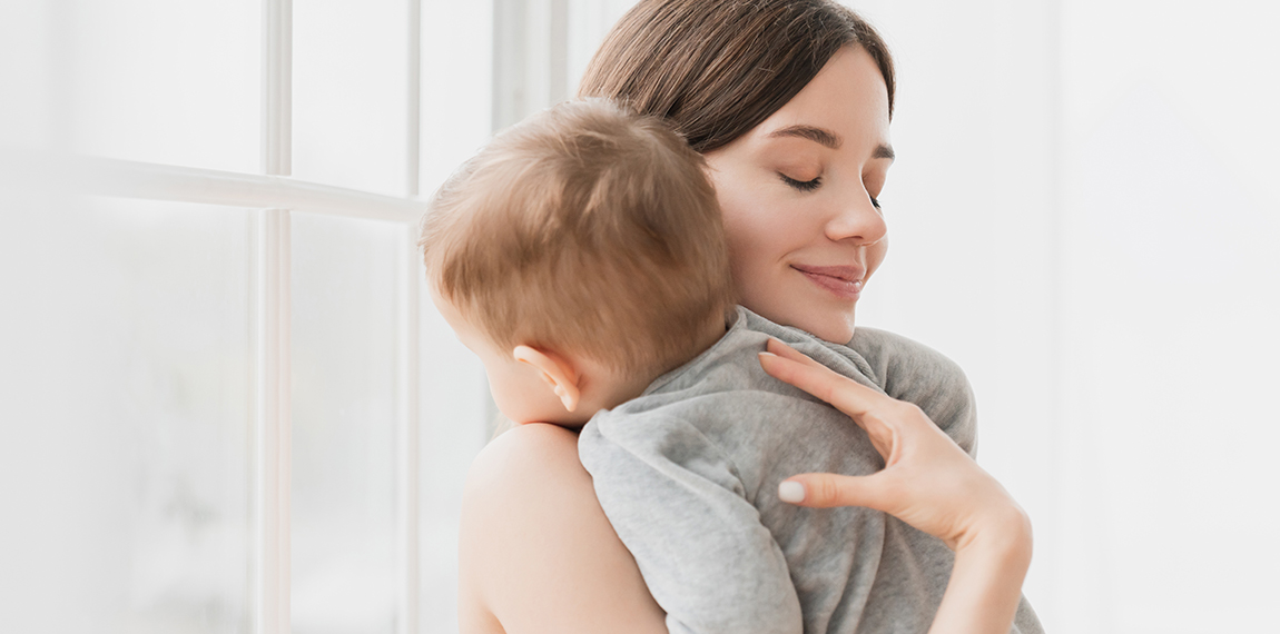 Young single mother lulling cradling her little small son daughter toddler infant newborn baby