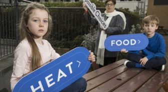 Two kids holding signs with a lady in the back