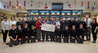 Students and faculty receiving a cheque at a school