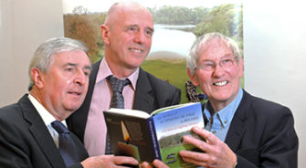 Three men holding a book