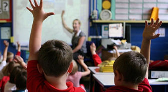 Children holding their hands up in a class