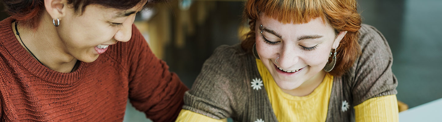 Two girls laughing while looking down