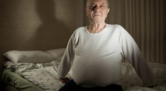 A old man sitting on his bed