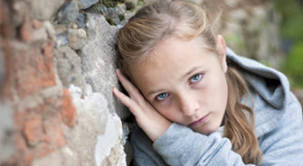 A sad girl leaning on a wall