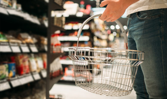 A man carrying an empty shopping basket at a supermarket