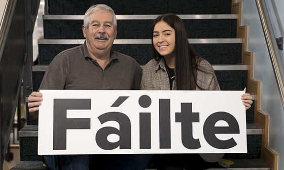 A father and mother holding a welcome banner