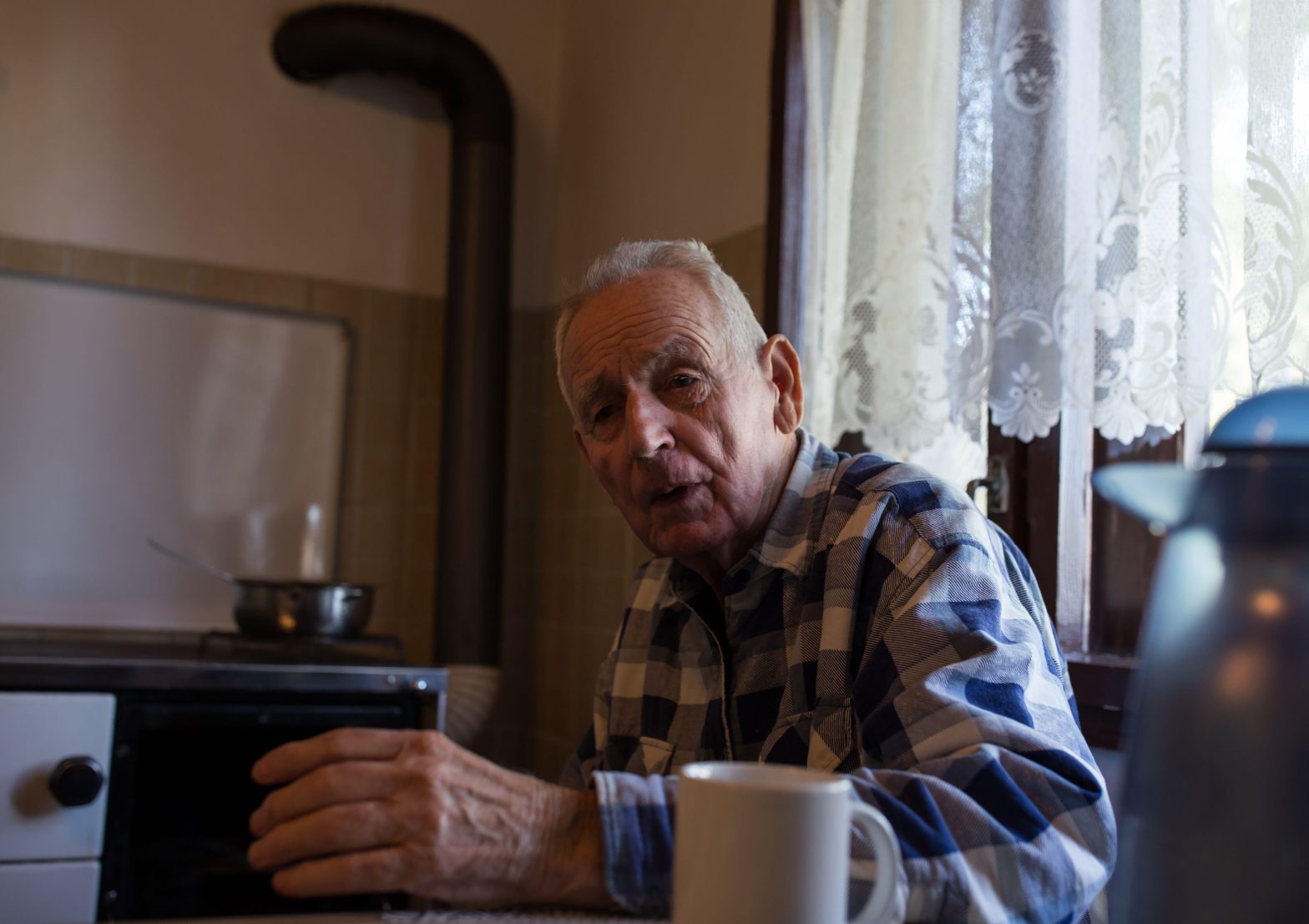 Senior man drinking tea at home in vintage interior of kitchen
