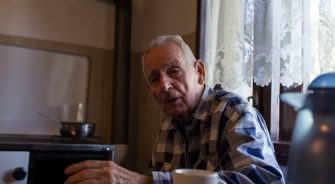 Senior man drinking tea at home in vintage interior of kitchen