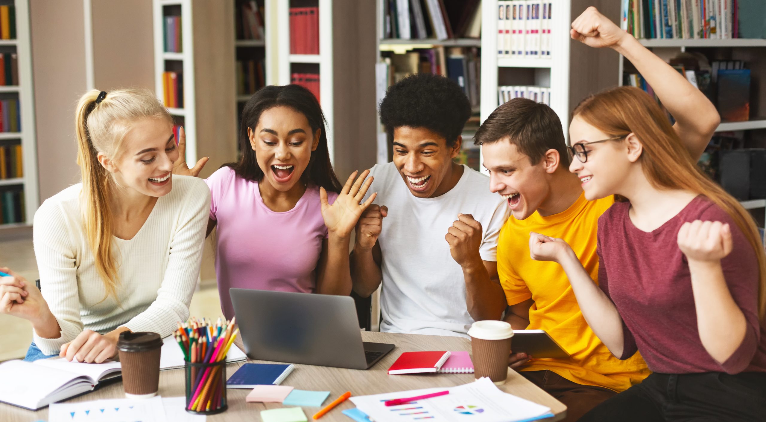 Group of young happy students enjoying test results in library