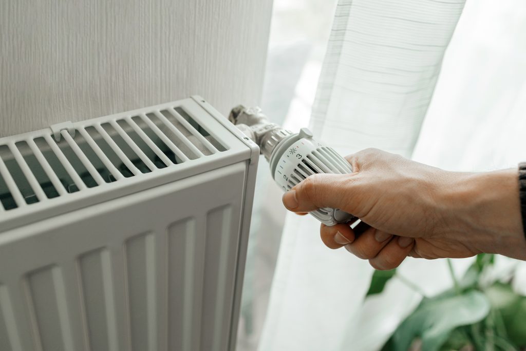 A man regulates the temperature on the radiator at home. Rising prices for heating in households. SVP Social Justice energy poverty in Ireland.
