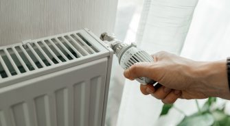 A man regulates the temperature on the radiator at home. Rising prices for heating in households. SVP Social Justice energy poverty in Ireland.