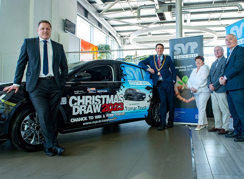 Three people standing next to a car up for raffle
