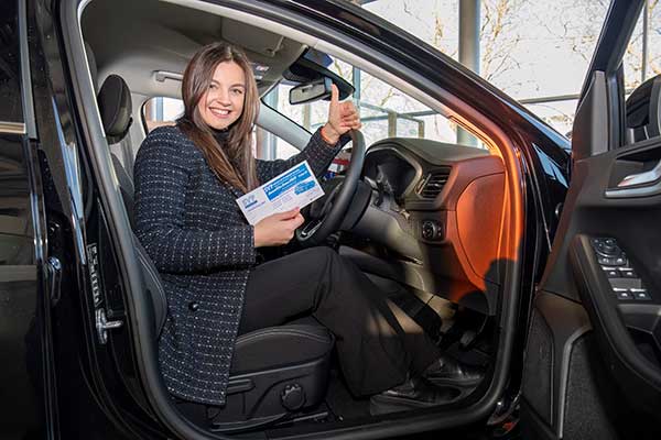 Woman sitting in car holding a raffle ticket