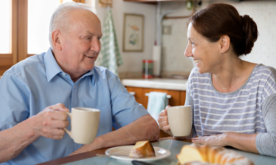 Female caregiver helping senior man, kitchen