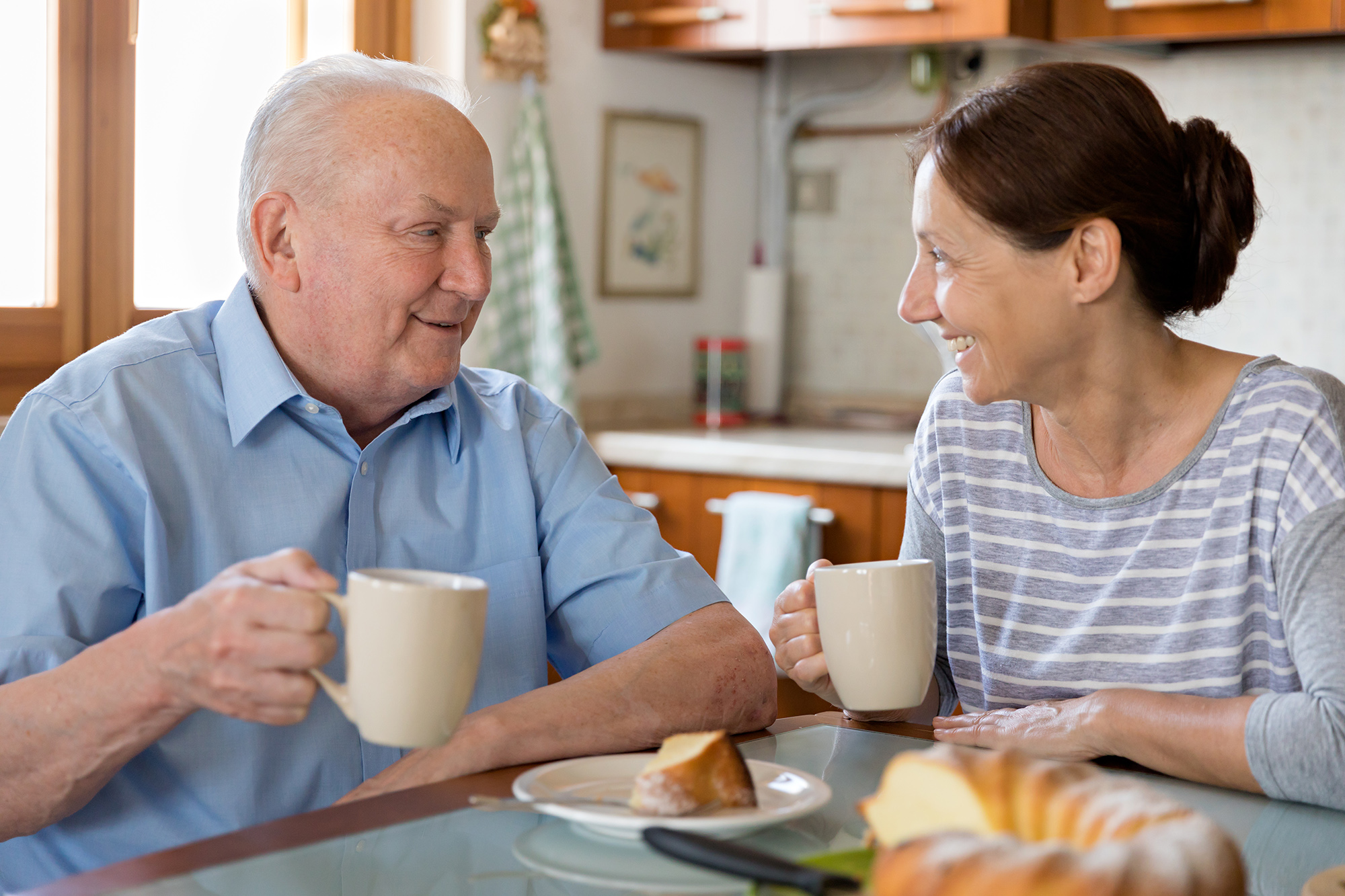 Impact Stories - Female caregiver helping a senior man in the kitchen